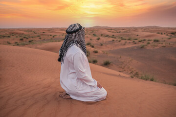 Young man praying in desert during ramadan month