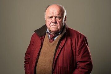 Elderly man with a sad expression on his face. Studio shot against a grey background.