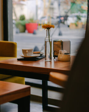 Latte and a cookie inside a city coffee shop and over a table with a yellow flower and beautiful interior design