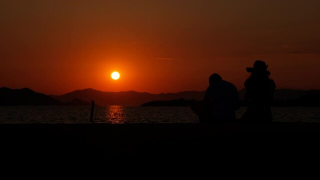 Silhouette of a young couple taking pictures at sunset