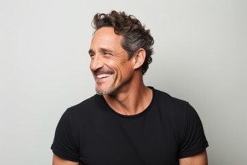Portrait of a handsome middle-aged man laughing over gray background