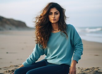Serene young woman sitting on a beach at sunset in casual attire