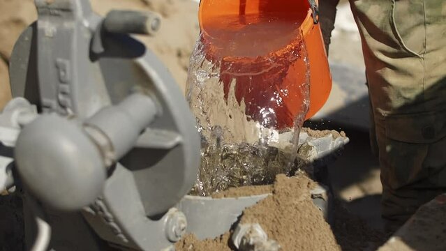 worker at a construction site pours water with a bucket