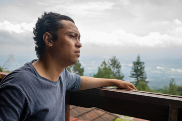 Fototapeta premium Man sitting near fence and looking the landscape mountain. The photo is suitable to use for calm enjoyed activity, leisure activity and park background.