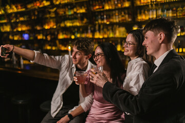 Friends rejoice at meeting with delicious cocktails in cozy pub. Young guy photography with close...