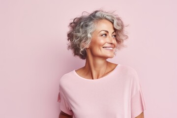 Portrait of a happy senior woman with curly hair on pink background