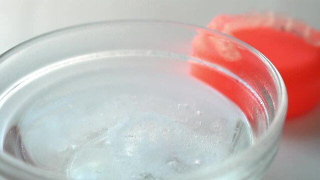 矯正歯科治療　マウスピースを洗うために洗浄剤を水に入れる女性