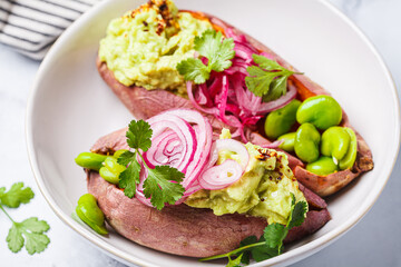 Baked sweet potato halves with guacamole, edamame beans, pickled red onion and cilantro.