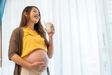 Happy smiling asian mother woman drinking fresh milk hugging with pregnancy baby in belly, woman pregnant, birth, preparation, maternity, protein, nutrition,calcium and vitamin.healthy concept - obrazy, fototapety, plakaty
