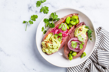 Baked sweet potato halves with guacamole, edamame beans, pickled red onion and cilantro.
