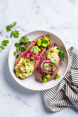 Baked sweet potato halves with guacamole, edamame beans, pickled red onion and cilantro.