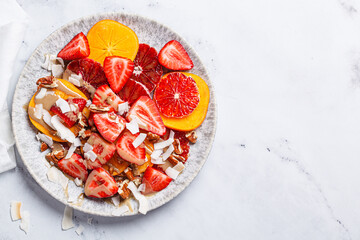 Fruit salad with persimmon, orange, strawberries, coconut chips and tahini.