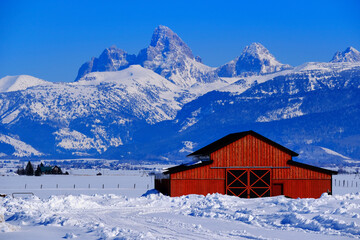 Teton Mountain Range Idaho Side Red Barn in Winter Blue Sky and Forest