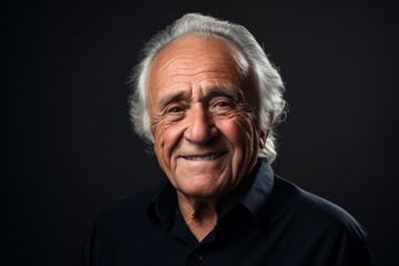 Portrait of a happy senior man smiling at the camera over black background.