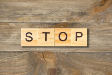 STOP word written on wood block on wooden table. top view.