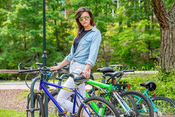 Chic Commute: Stunning Brunette College Student's Effortless Arrival on Campus by Bicycle, Poised...