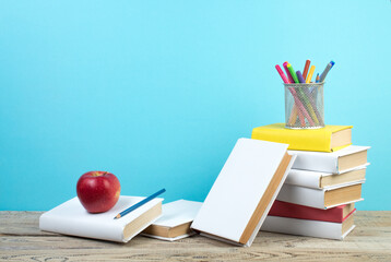 Books stacking. Books on wooden table and blue background. Back to school. Copy space for ad text.