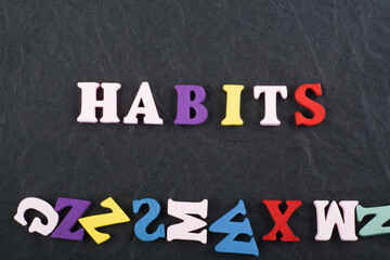 HABITS word on black board background composed from colorful abc alphabet block wooden letters,...