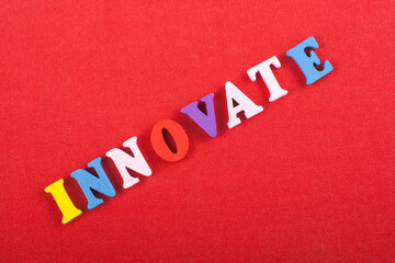 INNOVATE word on red background composed from colorful abc alphabet block wooden letters, copy...