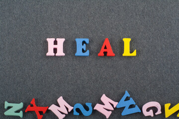 HEAL word on black board background composed from colorful abc alphabet block wooden letters, copy space for ad text. Learning english concept.