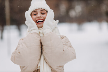 Happy smiling young woman portrait dressed coat scarf hat and mittens enjoys winter weather at snowy winter park - 767207053