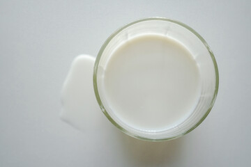 Obraz na płótnie Canvas 上から見たグラスに入った牛乳とこぼれた牛乳　白背景