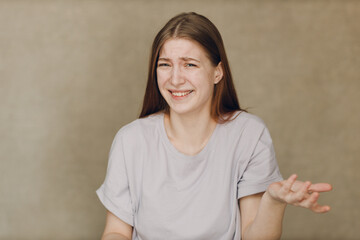 Portrait of young caucasian surprised skeptical woman looking at camera against beige background - 767208697