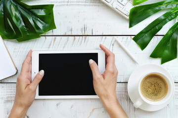 Person using digital tablet with empty black screen on white wooden table, top view