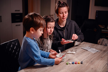 Focused siblings engage in a chemistry experiment with the help of a young woman, depicting a scene of shared learning and family bonding at home