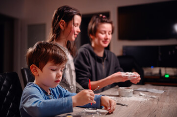A focused family immerses in creativity, with children shaping clay and a young boy coloring, capturing a moment of artistic expression and familial bonding