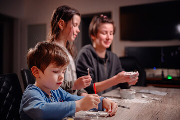 A focused family immerses in creativity, with children shaping clay and a young boy coloring,...