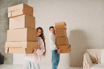 Happy young family couple man and woman carry cardboard boxes to new real estate apartment. Moving and delivery concept. - 767210663