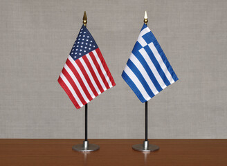 USA and Greece tabletop flags on gray blurred background