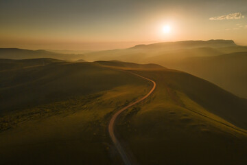 Fototapeta na wymiar Road in the green hills at foggy sunrise. Gil-Su valley in North Caucasus, Russia.