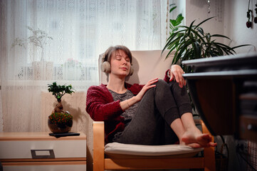 With closed eyes and headphones on, a woman is immersed in a private concert, feeling every beat in...