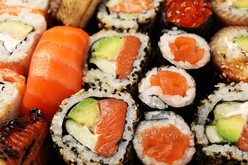 Different tasty sushi rolls as background, closeup