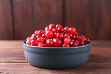 Fresh ripe cranberries in bowl on wooden table, closeup