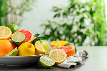 Different fresh citrus fruits on grey table against blurred background, closeup. Space for text
