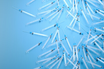 Multiple Disposable Medical Syringes Spread on a Vivid Blue Background - obrazy, fototapety, plakaty