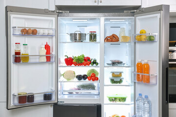 Modern open refrigerator full of different products in kitchen