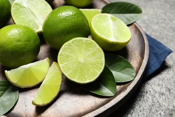 Kissenbezug Fresh ripe limes and leaves on grey table, closeup © New Africa