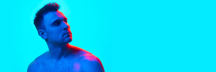 Banner. Handsome man with bare shoulders looking away in neon light against gradient blue...