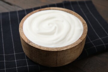 Fototapeta na wymiar Delicious natural yogurt in bowl on wooden table, closeup