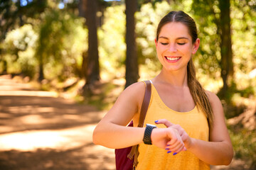 Young Active Woman Checking Activity Monitor On Smart Watch Hiking Along Trail Through Countryside - 767219844