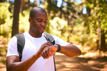 Young Active Man Checking Activity Monitor On Smart Watch Hiking Along Trail Through Countryside - 767220079