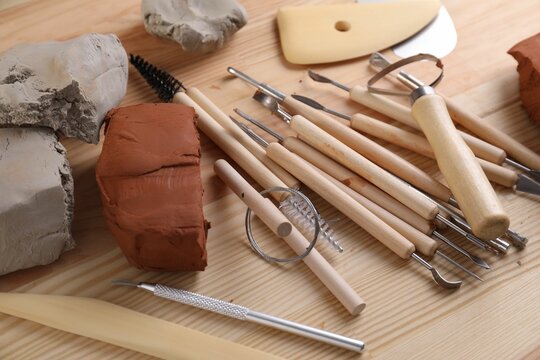 Clay and set of modeling tools on wooden table, closeup