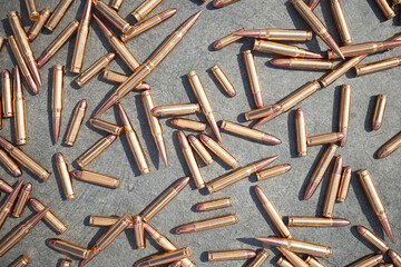 Illuminated Rifle Ammunition Scattered Across a Rough Stone Surface - obrazy, fototapety, plakaty