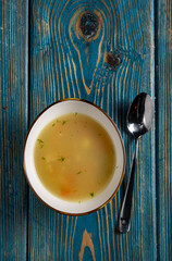 Chicken soup in a bowl on a blue wooden background. Top view.