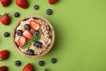 Tasty oatmeal with strawberries, blueberries and almond petals in bowl surrounded by fresh berries...