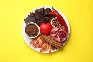 Natural aphrodisiac. Different products and heart model on yellow background, top view